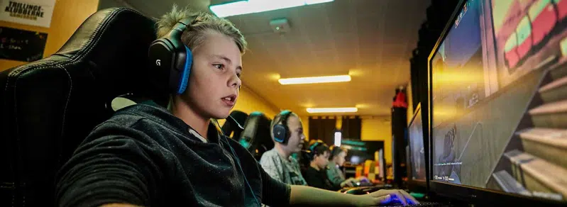 Dreng med øretelefoner spiller på computer